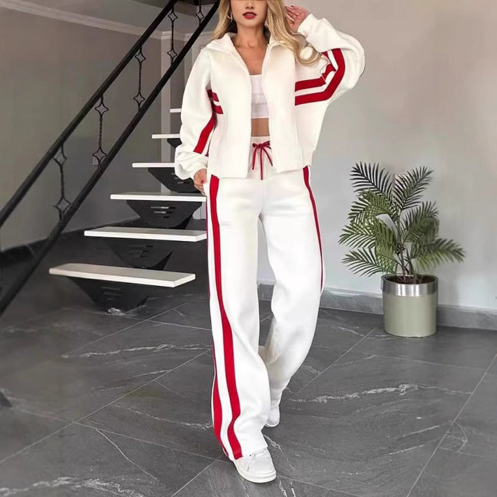 Model in de witte set met rode strepen, vooraanzicht van het open jack en de broek, staand bij een trap. 1