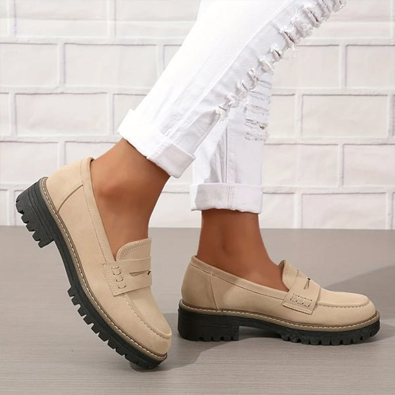 Beige loafers met zwarte plateauzool, gedragen met gescheurde witte broek, zijaanzicht terwijl de ene voet wordt opgetild. 3