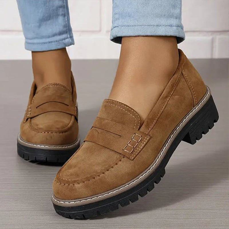 Bruine loafers met contraststiksels en dikke zwarte zool, gedragen met lichtblauwe spijkerbroek, close-up van de voorkant. 5
