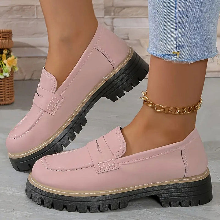 Roze loafers met glad oppervlak en dikke zwarte plateauzool, gedragen met een gouden enkelbandje en korte spijkerbroek. 11
