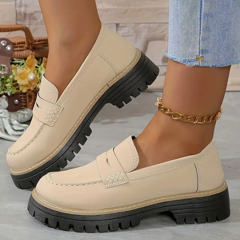 Beige loafers met glad oppervlak en zwarte plateauzool, gedragen met gouden enkelbandje en omgeslagen spijkerbroek. 14
