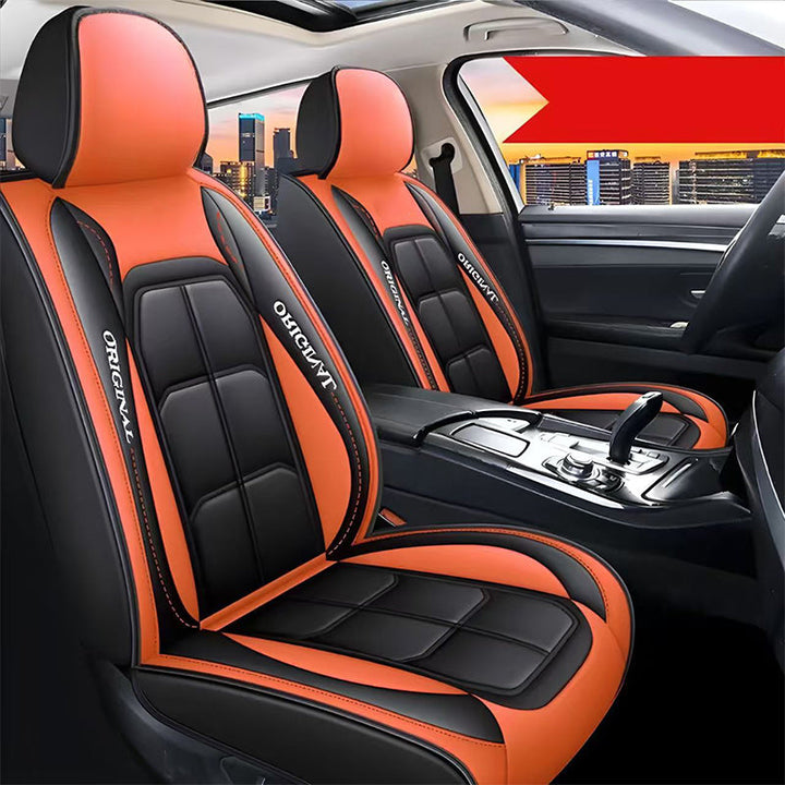 Twee voorstoelen met zwart-oranje hoezen in een auto, met op de achtergrond de stad bij zonsondergang. 15