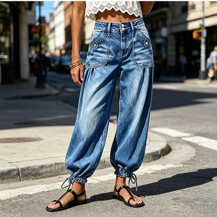Voorkant van de blauwe barreljeans gedragen op straat, met grote zakken met knoopjes en gestrikte zoom bij zwarte sandalen. 2