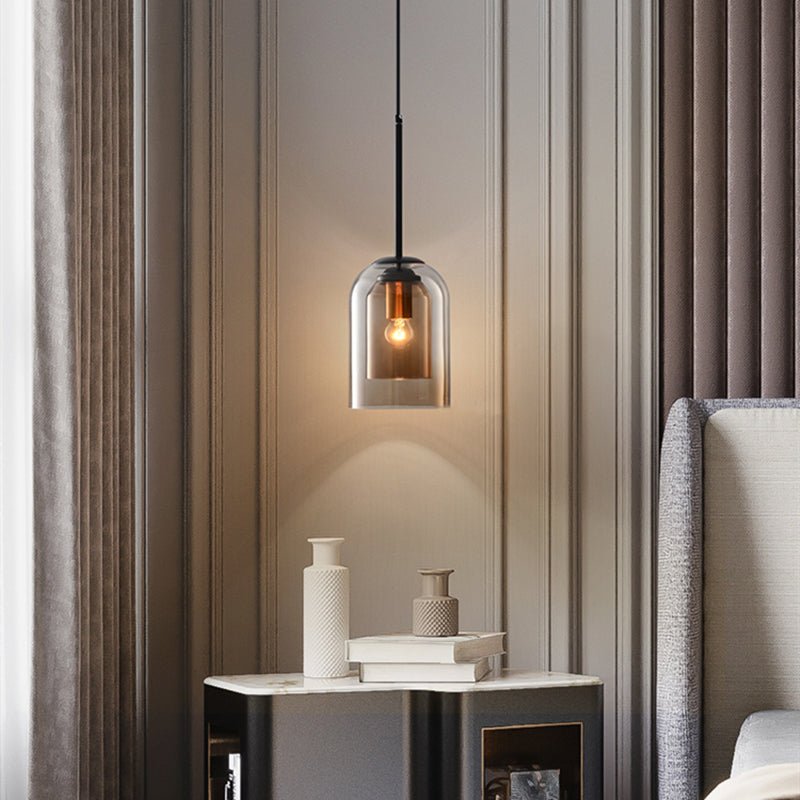 Amberkleurige glazen hanglamp boven een nachtkastje in een slaapkamer met beige wandpanelen en gordijnen 2