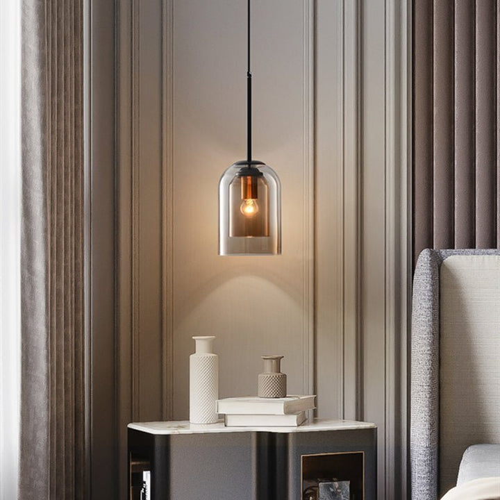 Amberkleurige glazen hanglamp boven een nachtkastje in een slaapkamer met beige wandpanelen en gordijnen 2
