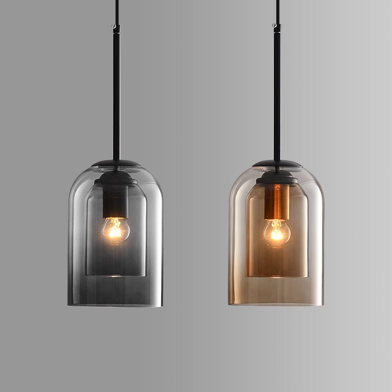 Twee hanglampen naast elkaar: links in grijs rookglas, rechts in amberkleurig glas 2