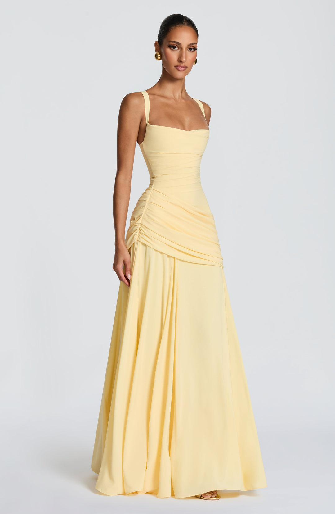 Lichtgele maxi-jurk in driekwartaanzicht op een model, met brede bandjes, geplooide taille en soepel vallende rok. 3