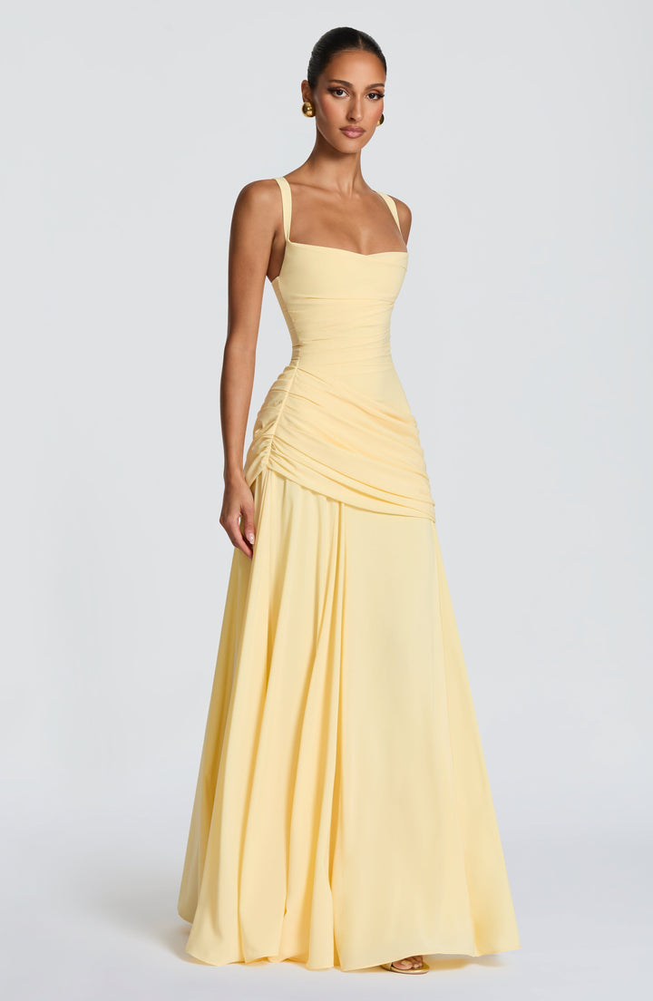 Lichtgele maxi-jurk in driekwartaanzicht op een model, met brede bandjes, geplooide taille en soepel vallende rok. 3