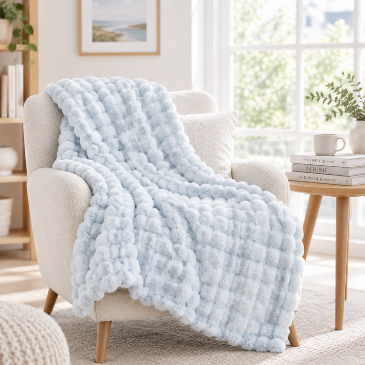 Lichtblauwe pluizige bolletjesdeken over een crèmekleurige fauteuil voor een groot raam 17