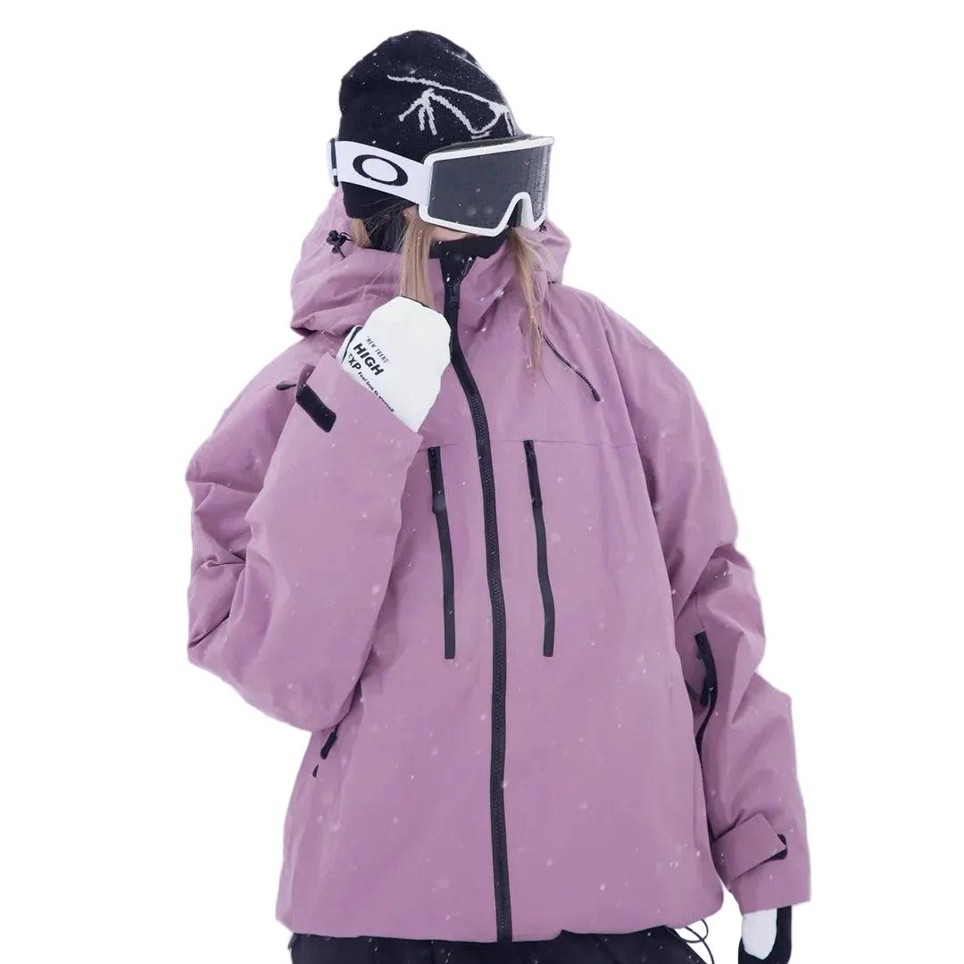 Model in roze-paarse sneeuwjack met capuchon, schuin van voren gezien met een hand opgeheven, tegen een sneeuwachtergrond. 2