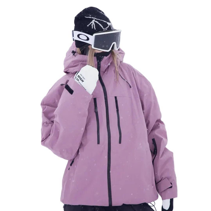 Model in roze-paarse sneeuwjack met capuchon, schuin van voren gezien met een hand opgeheven, tegen een sneeuwachtergrond. 2