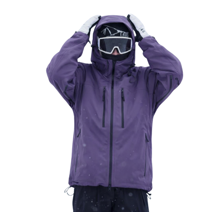 Model in paarse sneeuwjack met capuchon, beide handen aan het hoofd, met skibril, zichtbare ritszakken op de borst en trekkoord aan de zoom. 1