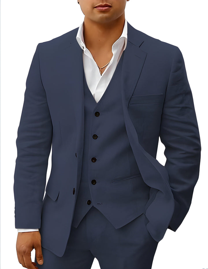 Close-up van het pak in donkerblauw gedragen door een model, gilet met bruine knopen en borstzakje. 6