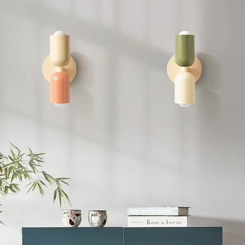 Twee wandlampen in crème met perzik en in groen met crème, boven een blauwgroen kastje met kopjes en boeken. 14