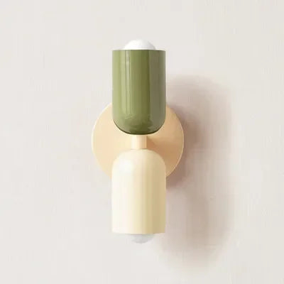 Close-up van een wandlamp met een olijfgroene bovenkap, crème onderkap en crème wandplaat tegen een lichte muur. 18