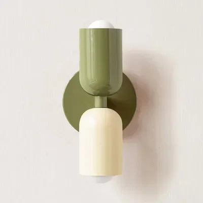 Close-up van een wandlamp in olijfgroen en crème tegen een lichte muur, met bolvormige lampen boven en onder. 15