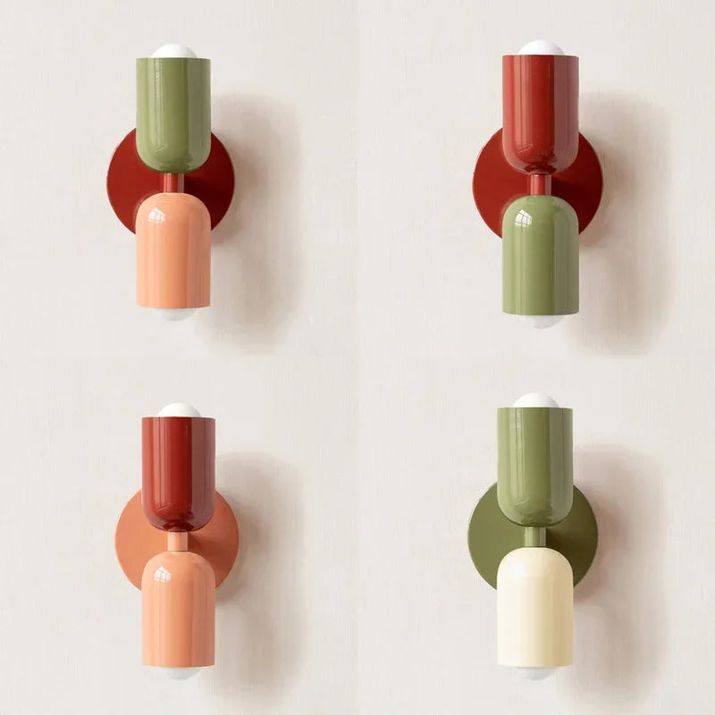 Vier wandlampen in verschillende kleurcombinaties van groen, rood, perzik en crème naast elkaar op een lichte muur. 12