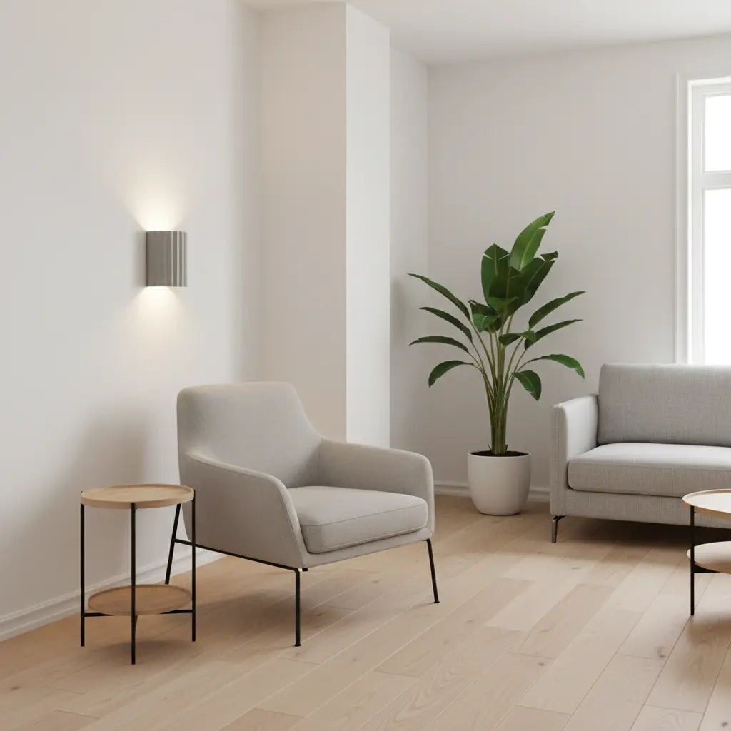 Lichtgrijze wandlamp aan een witte muur in een woonkamer met fauteuil, bank en grote kamerplant 5