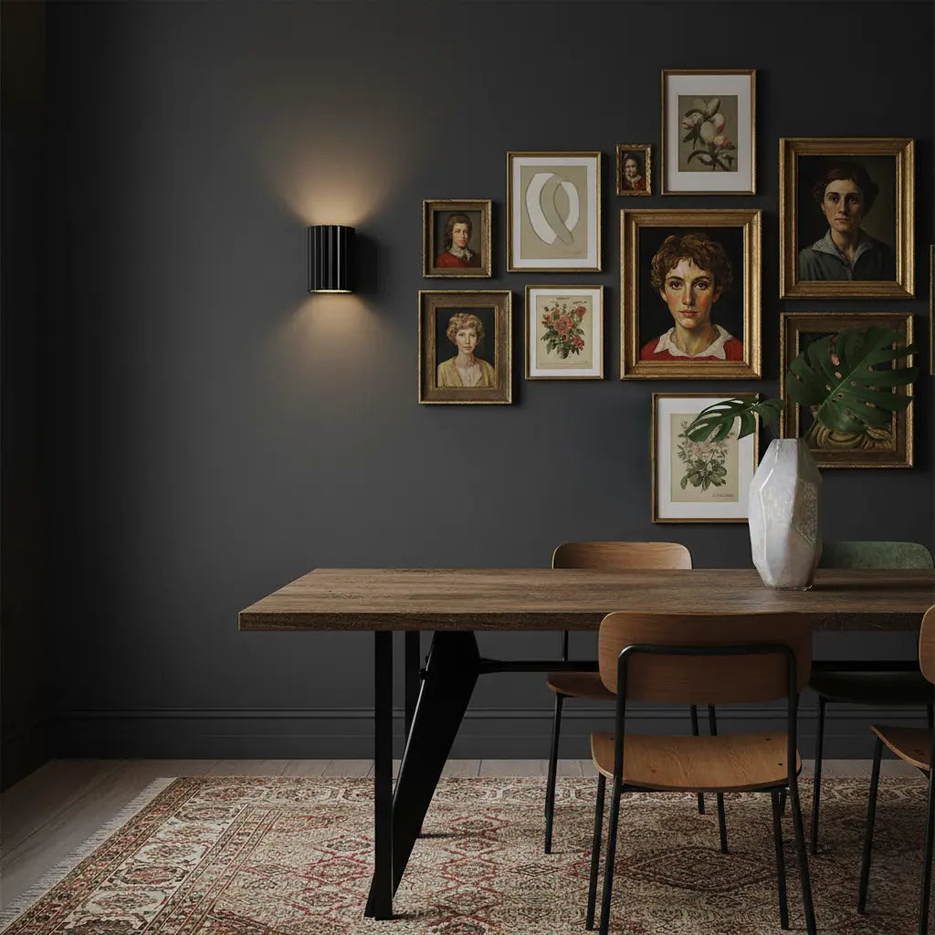 Zwarte wandlamp aan een donkergrijze muur naast een wand met ingelijste portretten en een eettafel 6