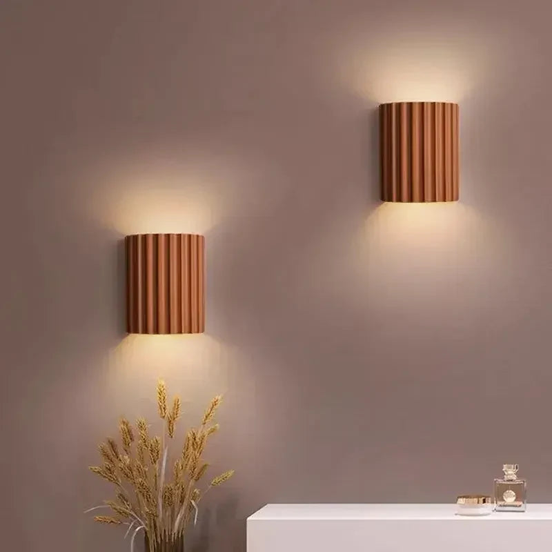 Twee terracotta wandlampen aan een muur, met licht naar boven en onder, boven een wit meubel met droogbloemen 8