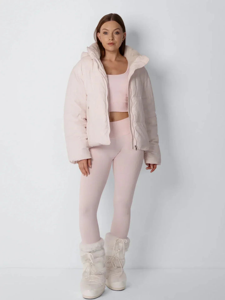 Volledig vooraanzicht van model in open roze pufferjack met bijpassende legging en bontlaarzen 10