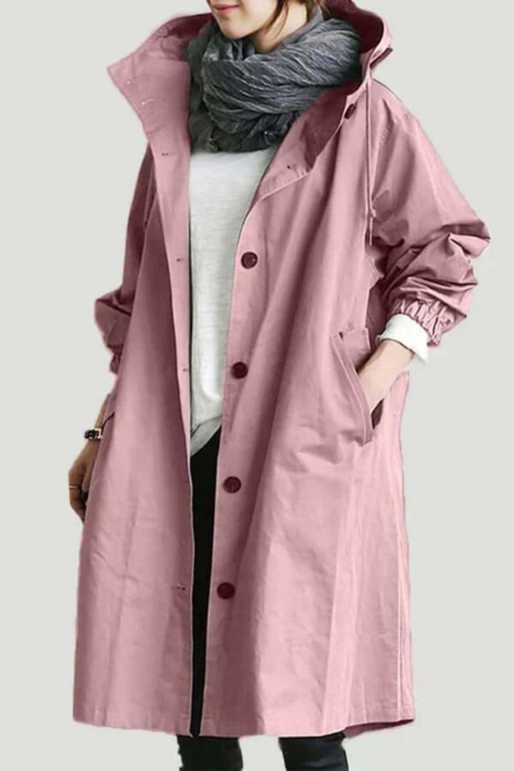 Roze lange jas met capuchon gedragen met grijze sjaal, witte trui en hand in de zak 1