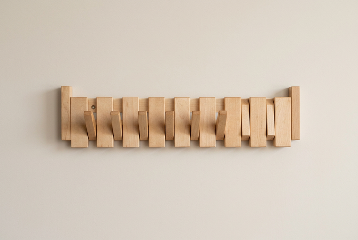 Lichte houten kapstok met zeven uitgeklapte haken en twee ingeklapte, voorkant op een beige muur 13