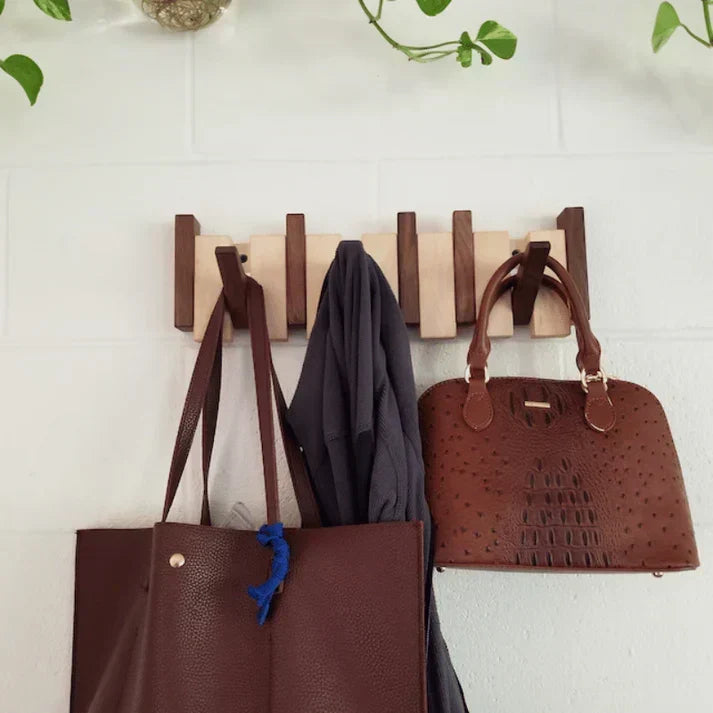 Wandhanger tegen een witte bakstenen muur met twee bruine leren tassen en een grijs kledingstuk 3