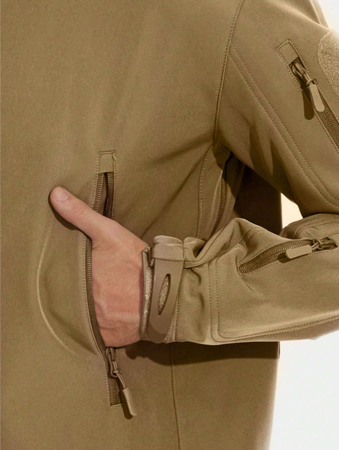 Detail van de beige jas: een hand in de ritszak, met verstelbare manchetband en ritszakje op de mouw. 13